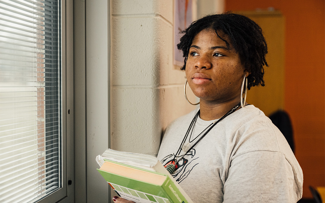 A student looking out a window from the classroom