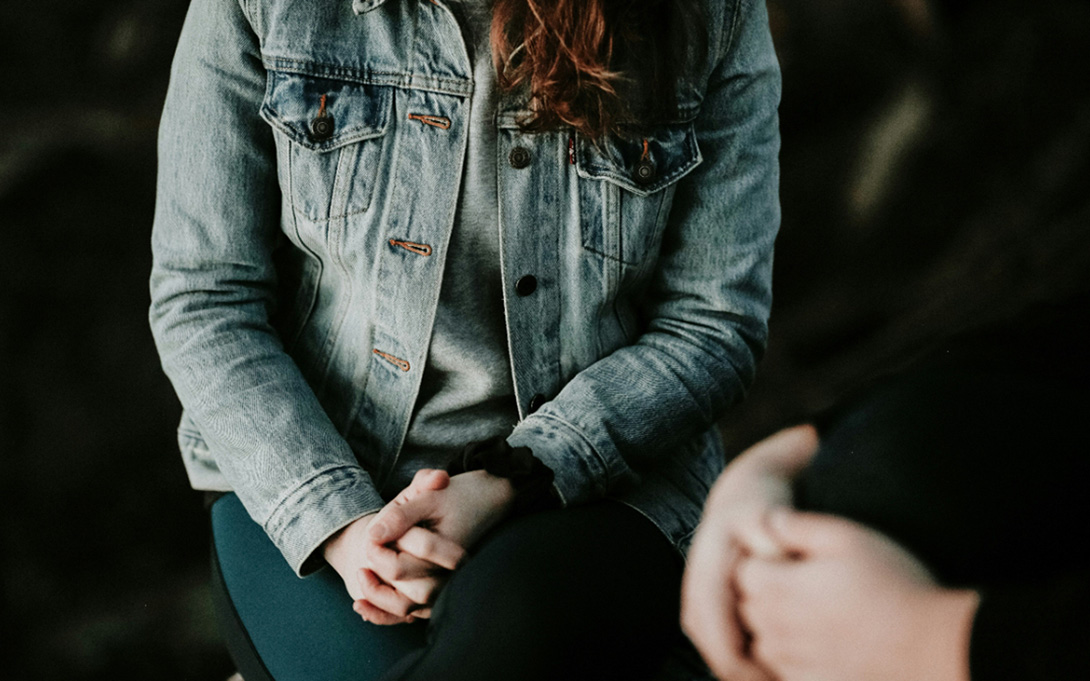 a young woman sitting and talking to another person