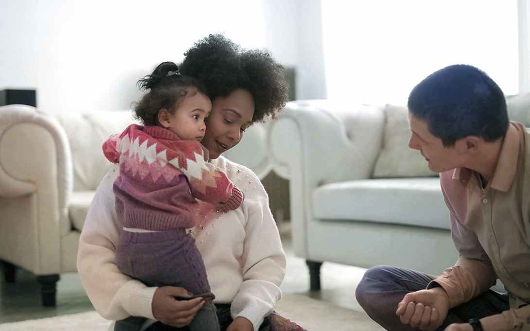 a young couple having a play time with their toddler daughter on carpet