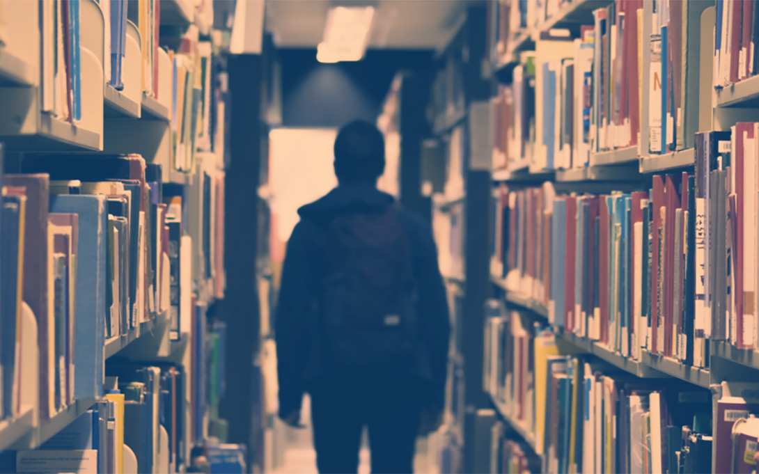 a high school student walking between shelves in a library