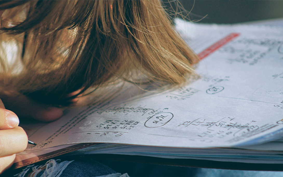 an elementary student writing on paper solving a math problem