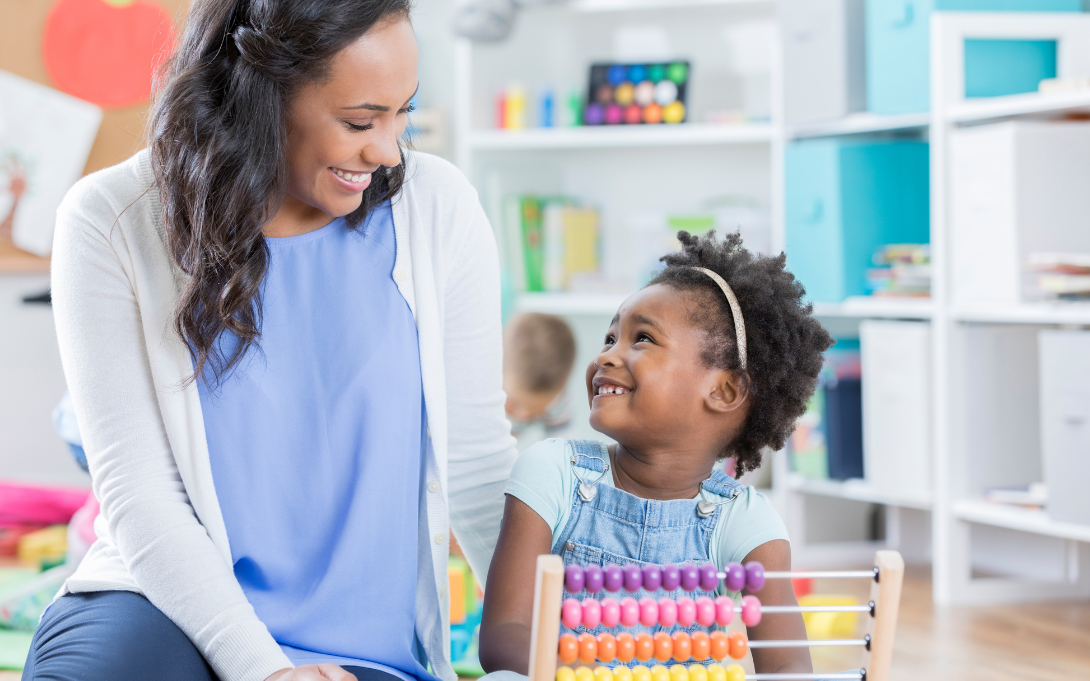 Teacher and child smiling at each other while using an abacus