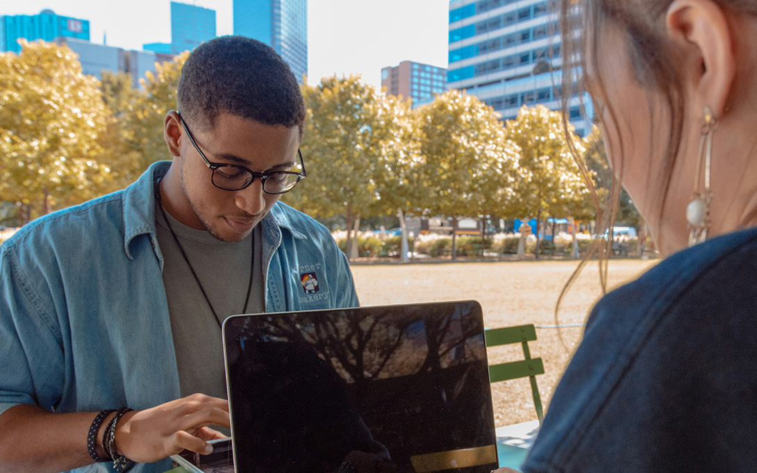 Two students studying outdoor on laptops