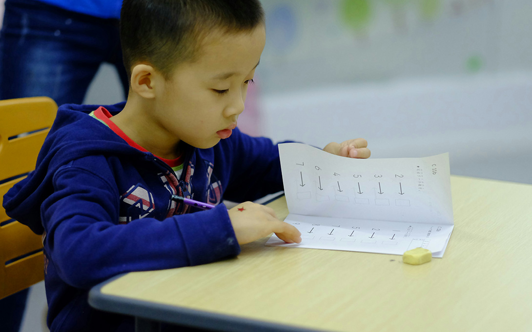 an kindergartener looking at 2 pages of math problems