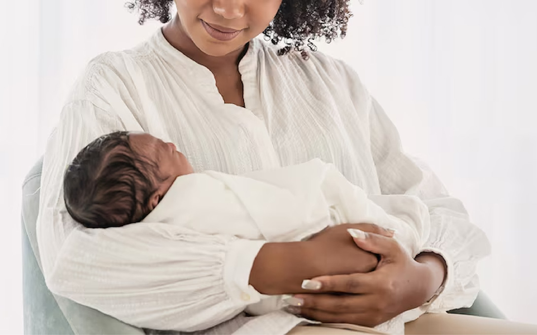 An African American woman holding her newborn infant