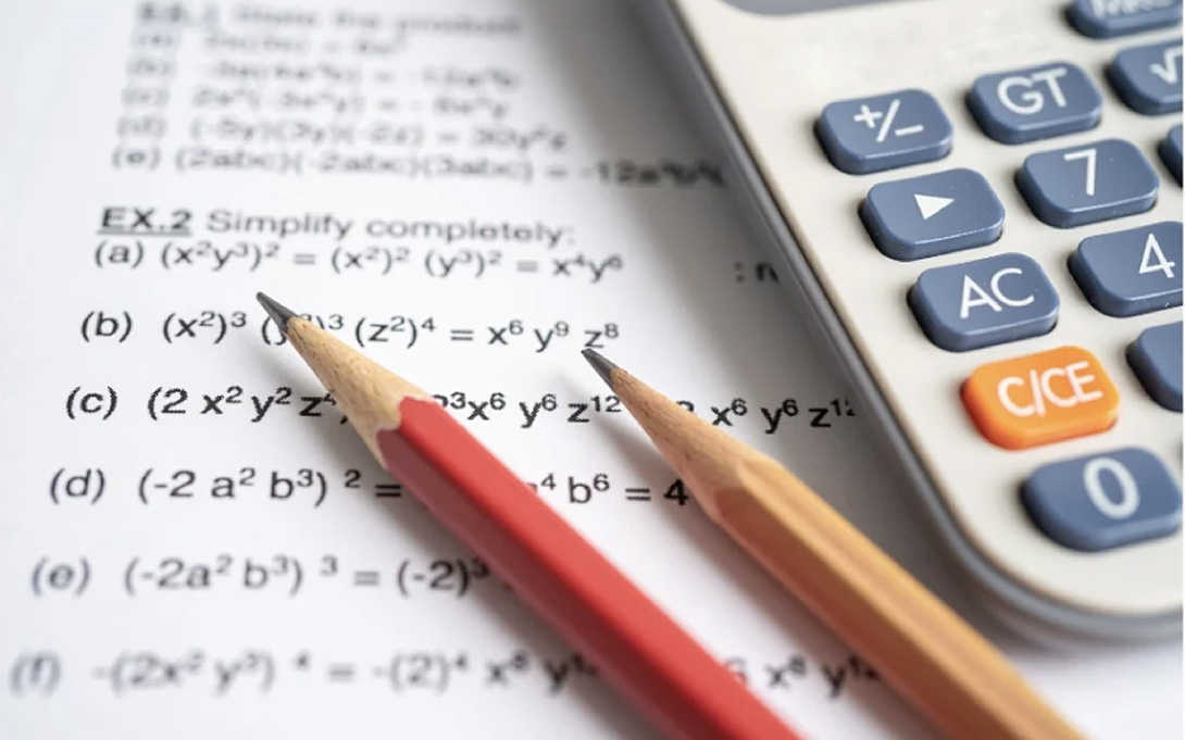 Two pencils lying next to a calculator 