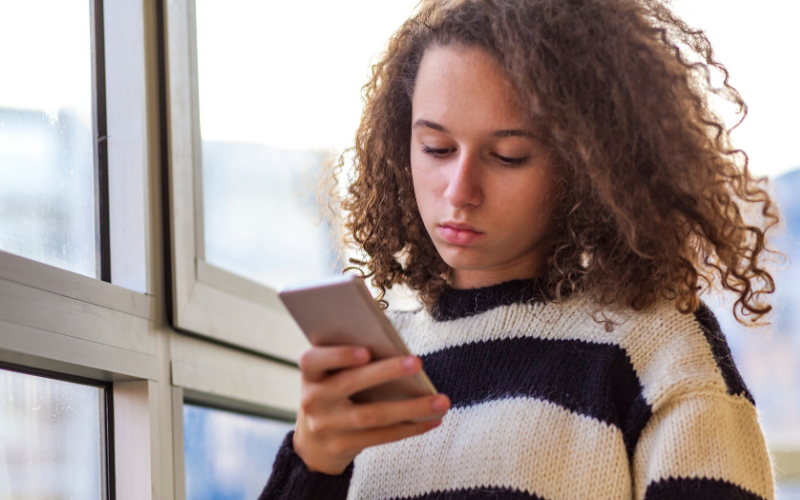 Teenager looking at a phone by the windows