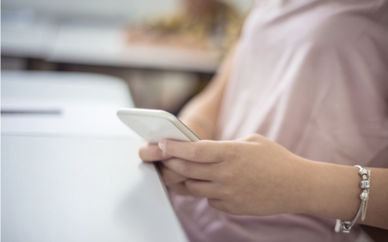 Person looking at a cell phone at a desk in a classroom
