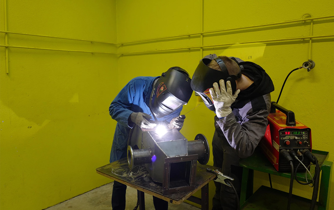 two students learning to weld
