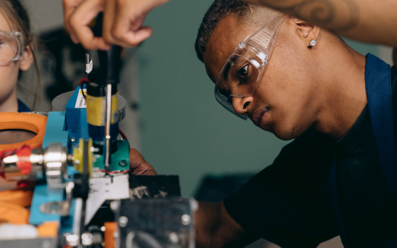 Student with safety goggles using a screwdriver on a tool or machine