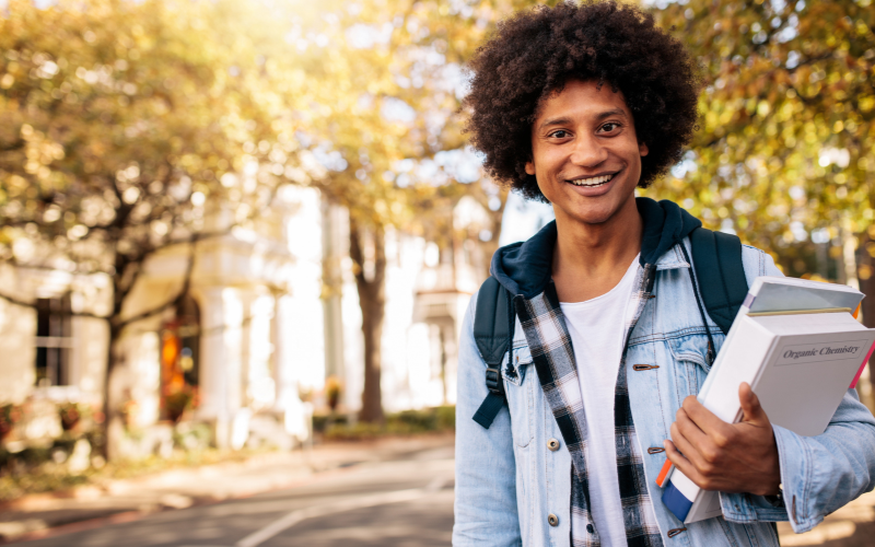 Person holding organic chemistry book on a tree-lined street 