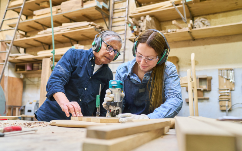 Teacher watching a student work with woodworking tool