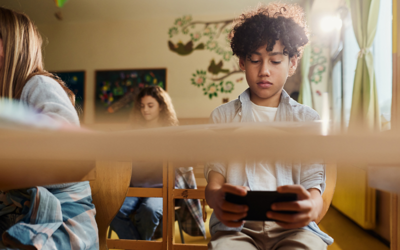 Kid in class looking at cell phone under the desk