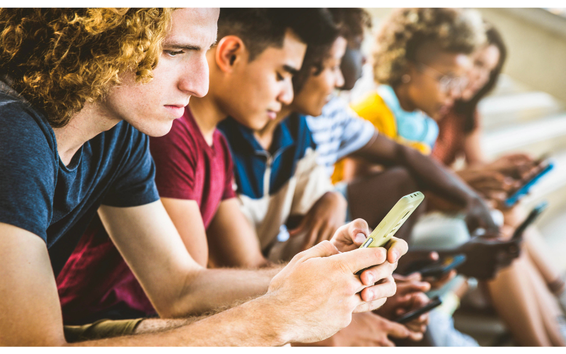 teens sitting in a row looking at phones