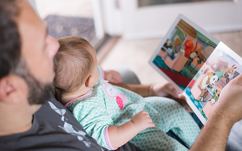 a guardian reading a picture book to a young baby
